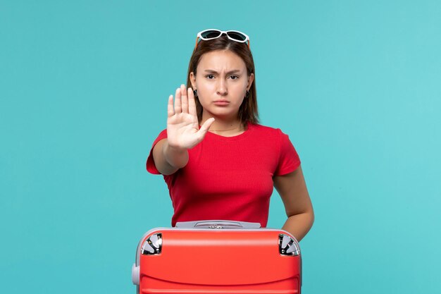 Vista frontal de las mujeres jóvenes con bolsa roja que muestra la señal de pare en el espacio azul