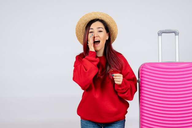 Vista frontal de las mujeres jóvenes con bolsa rosa con tarjeta bancaria en la pared blanca