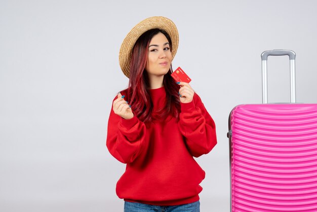 Vista frontal de las mujeres jóvenes con bolsa rosa con tarjeta bancaria en la pared blanca