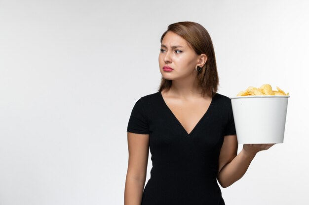 Vista frontal de las mujeres jóvenes en camisa negra con papas fritas en la superficie blanca