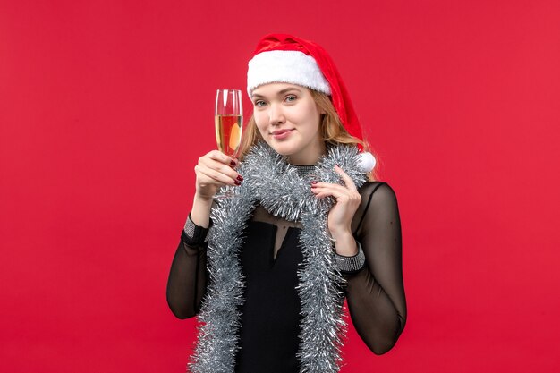 Foto gratuita vista frontal de las mujeres jóvenes celebrando el año nuevo con champán en la pared roja de color navideño