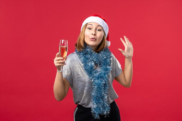 Vista frontal de las mujeres jóvenes celebrando el año nuevo en la pared roja color vacaciones de Navidad