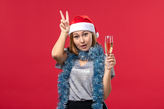 Vista frontal de las mujeres jóvenes celebrando el año nuevo que viene en la fiesta de Navidad de color rojo de la pared