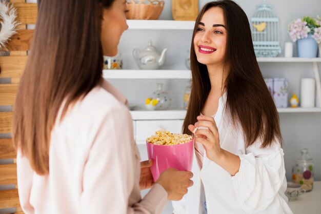 Vista frontal mujeres jóvenes compartiendo palomitas de maíz