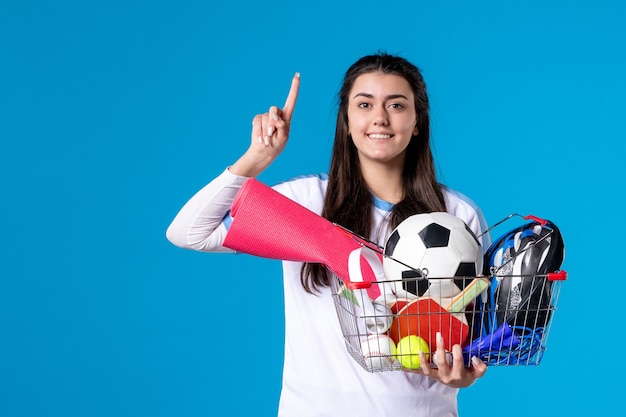 Vista frontal de las mujeres jóvenes después de las compras deportivas en la pared azul