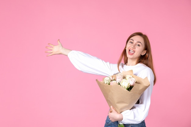 Vista frontal de las mujeres jóvenes con flores como presente el día de la mujer sobre fondo rosa marzo femenino horizontal mujer sensual fecha igualdad amor