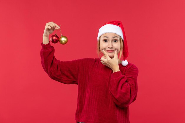 Vista frontal de las mujeres jóvenes con juguetes de navidad en la emoción de navidad de vacaciones de escritorio rojo