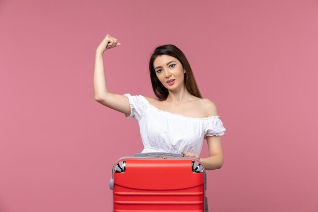 Vista frontal de las mujeres jóvenes preparándose para las vacaciones y flexionando sobre fondo rosa en el extranjero viaje por mar viaje viaje viaje