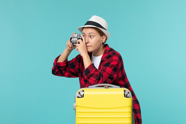 Vista frontal de las mujeres jóvenes preparándose para las vacaciones sosteniendo la cámara y tomando fotos en el espacio azul