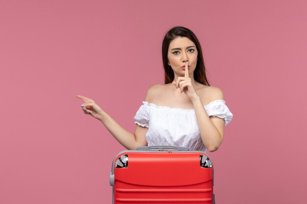 Vista frontal de las mujeres jóvenes preparándose para las vacaciones con su bolsa roja sobre fondo rosa viaje al extranjero viaje por mar viaje viaje