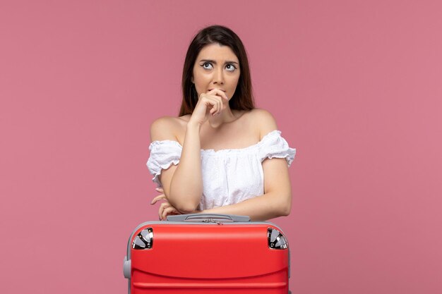 Vista frontal de las mujeres jóvenes preparándose para las vacaciones con su bolso en el piso rosa en el extranjero viaje por mar