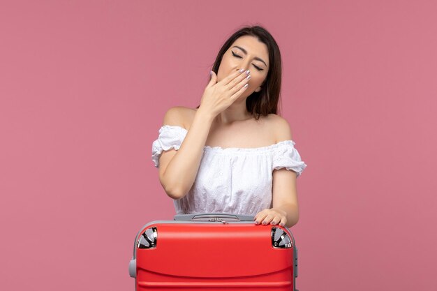 Vista frontal de las mujeres jóvenes preparándose para las vacaciones con su gran bolsa bostezando sobre fondo rosa en el extranjero viaje por mar viaje viaje viaje