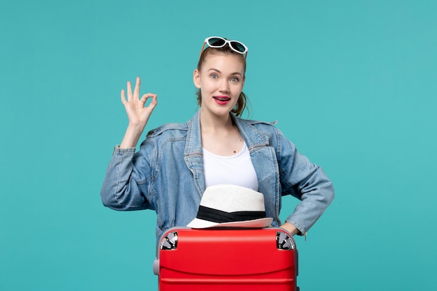 Vista frontal de las mujeres jóvenes preparándose para el viaje con bolsa roja y sombrero en el espacio azul