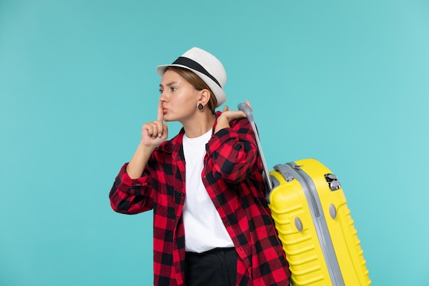 Vista frontal de las mujeres jóvenes que van de vacaciones con su bolsa amarilla en el escritorio azul