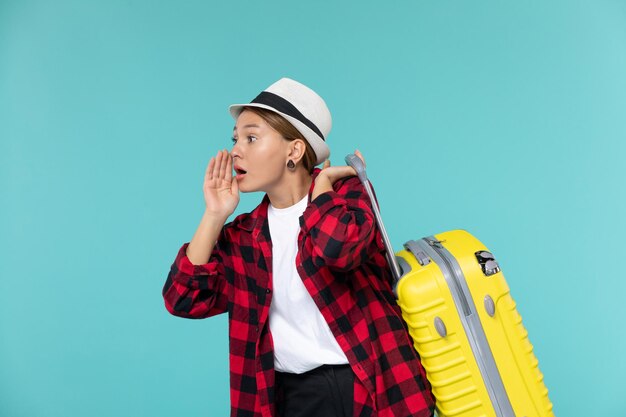 Vista frontal de las mujeres jóvenes que van de vacaciones con su bolso amarillo en el espacio azul claro