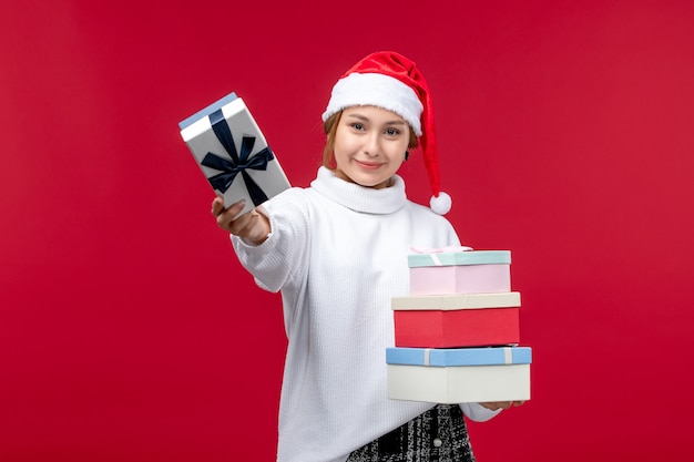 Vista frontal de las mujeres jóvenes con regalos de año nuevo en el escritorio rojo