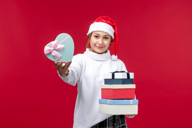 Vista frontal de las mujeres jóvenes con regalos de año nuevo en el escritorio rojo