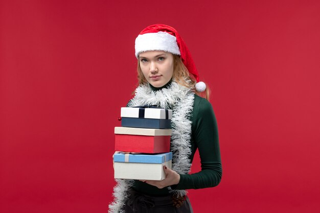 Vista frontal de las mujeres jóvenes con regalos de año nuevo sobre un fondo rojo.