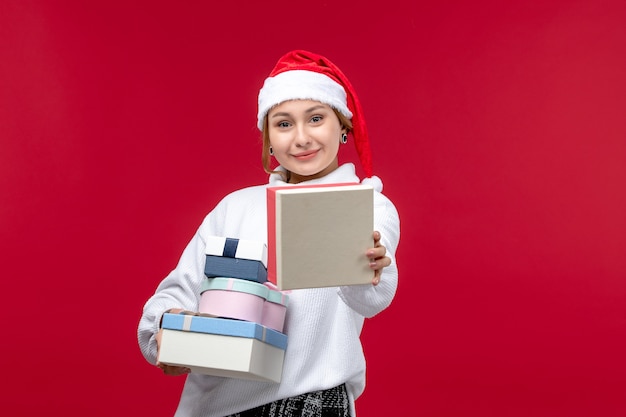 Vista frontal de las mujeres jóvenes con regalos navideños sobre un fondo rojo.