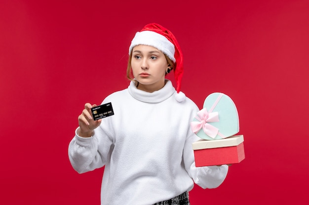 Vista frontal de las mujeres jóvenes con regalos y tarjetas bancarias en el fondo rojo.