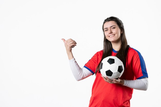 Vista frontal de las mujeres jóvenes en ropa deportiva con balón de fútbol en la pared blanca