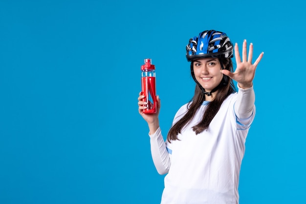 Vista frontal de las mujeres jóvenes en ropa deportiva con casco en la pared azul