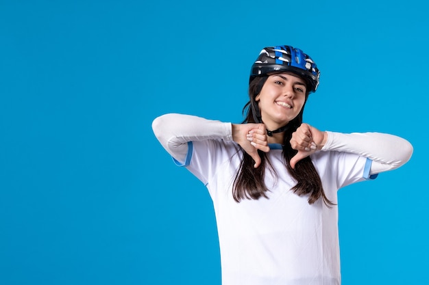 Vista frontal de las mujeres jóvenes en ropa deportiva con casco en la pared azul