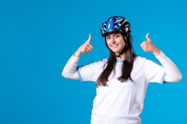 Vista frontal de las mujeres jóvenes en ropa deportiva con casco en la pared azul