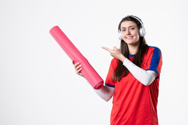 Vista frontal de las mujeres jóvenes en ropa deportiva con estera de yoga