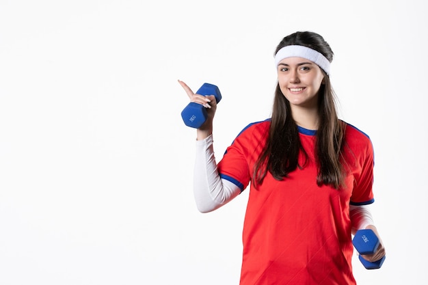 Vista frontal de las mujeres jóvenes en ropa deportiva con pesas azules en la pared blanca