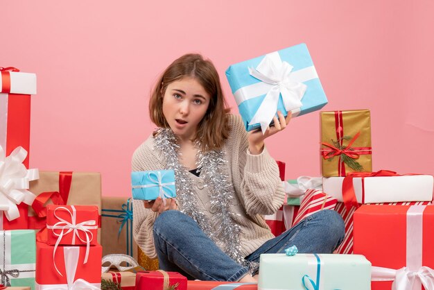 Vista frontal de las mujeres jóvenes sentados alrededor de diferentes regalos