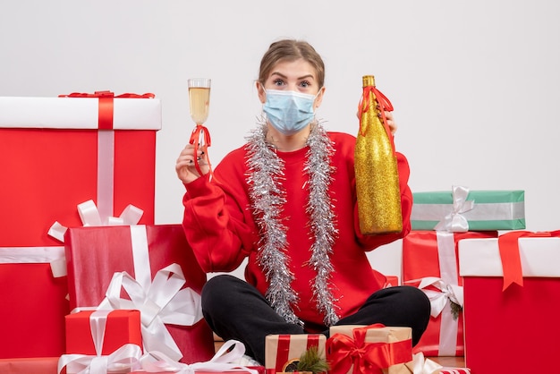 Vista frontal de las mujeres jóvenes sentados alrededor de regalos celebrando con champán