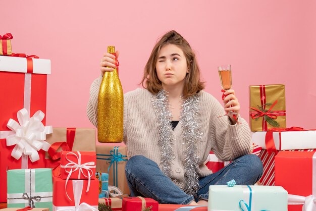 Vista frontal de las mujeres jóvenes sentados alrededor de los regalos de Navidad celebrando con champán