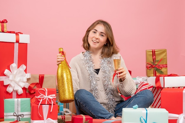 Vista frontal de las mujeres jóvenes sentados alrededor de los regalos de Navidad celebrando con champán