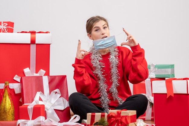 Vista frontal de las mujeres jóvenes sentados alrededor de los regalos de Navidad en máscara estéril