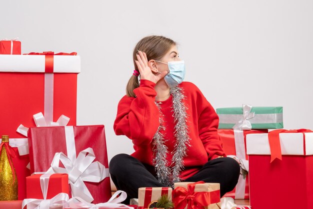 Vista frontal de las mujeres jóvenes sentados alrededor de los regalos de Navidad en máscara