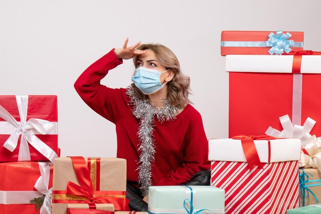 Vista frontal de las mujeres jóvenes sentados alrededor de los regalos de Navidad en máscara