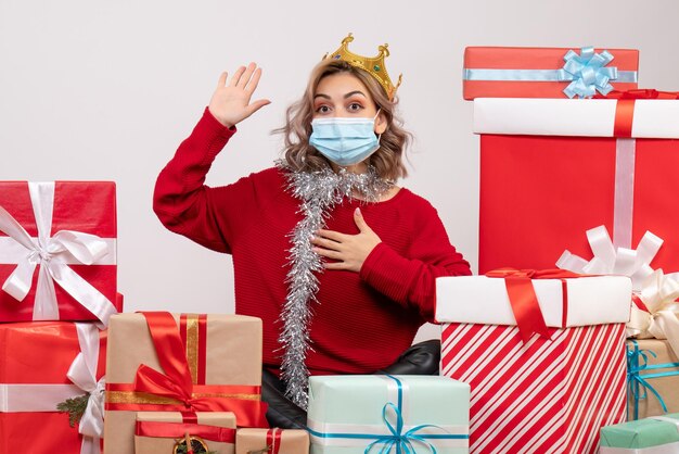 Foto gratuita vista frontal de las mujeres jóvenes sentados alrededor de los regalos de navidad en máscara