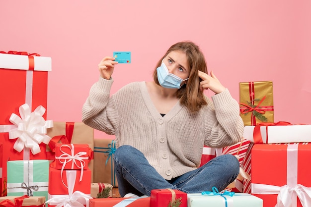 Vista frontal de las mujeres jóvenes sentados alrededor de regalos de Navidad en máscara