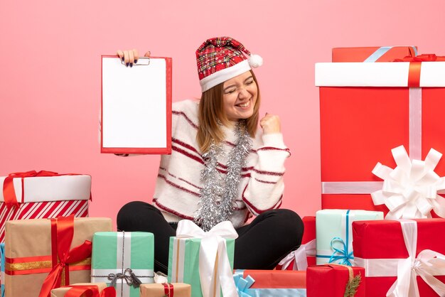 Vista frontal de las mujeres jóvenes sentados alrededor de regalos de Navidad con nota de archivo