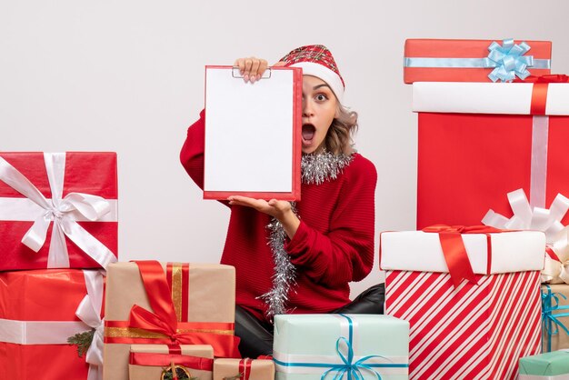 Vista frontal de las mujeres jóvenes sentados alrededor de regalos de Navidad con nota