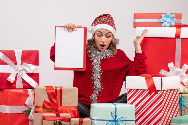 Vista frontal de las mujeres jóvenes sentados alrededor de regalos de Navidad con nota