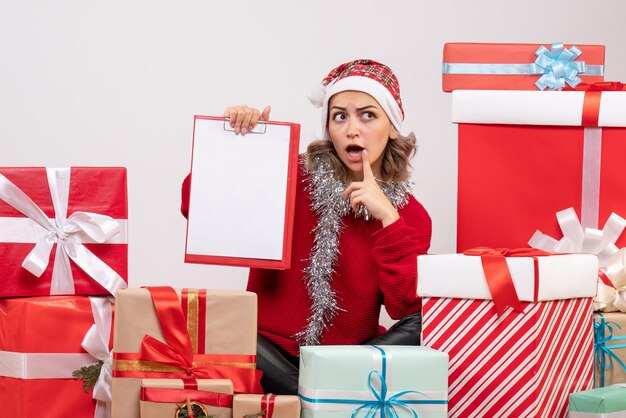 Vista frontal de las mujeres jóvenes sentados alrededor de regalos de Navidad con nota