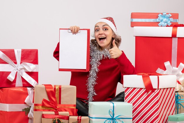 Vista frontal de las mujeres jóvenes sentados alrededor de regalos de Navidad con nota