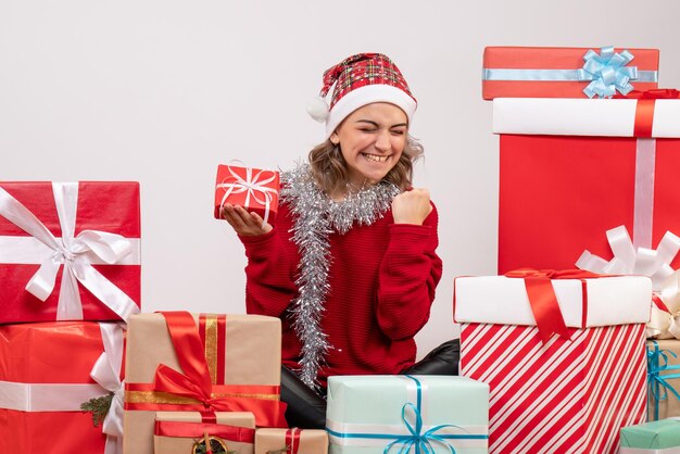 Vista frontal de las mujeres jóvenes sentados alrededor de los regalos de Navidad y regocijo