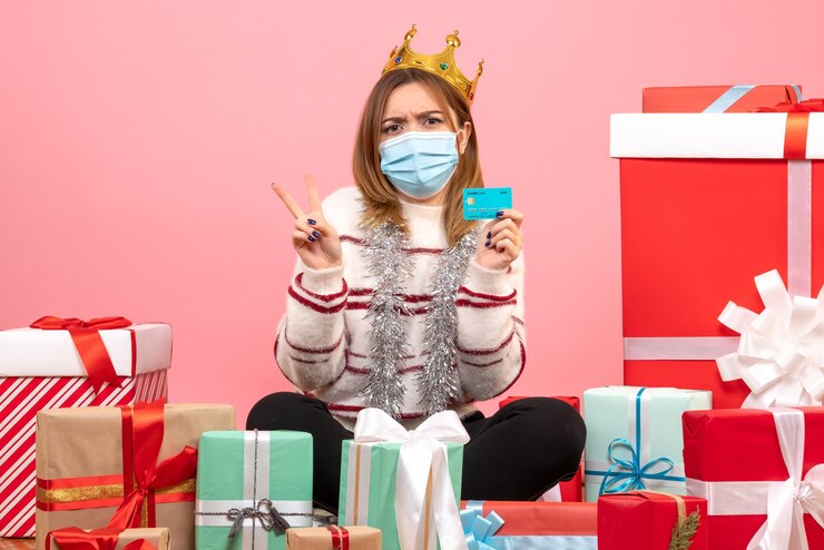 Foto gratuito vista frontal de las mujeres jóvenes sentados alrededor de regalos de navidad con tarjeta bancaria