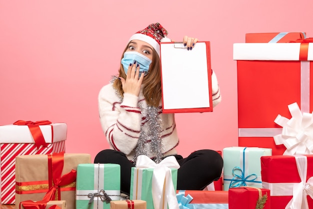 Vista frontal de las mujeres jóvenes sentados alrededor de regalos con nota de archivo