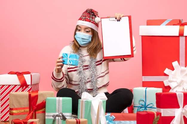 Vista frontal de las mujeres jóvenes sentados alrededor de regalos con nota de archivo