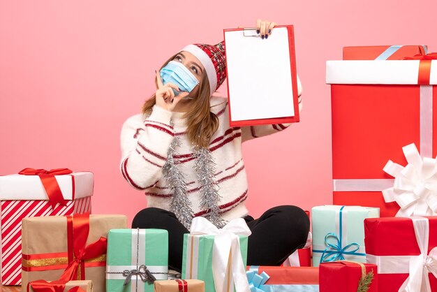 Vista frontal de las mujeres jóvenes sentados alrededor de regalos con nota de archivo