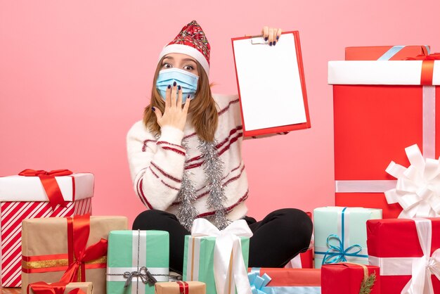 Vista frontal de las mujeres jóvenes sentados alrededor de regalos con nota de archivo